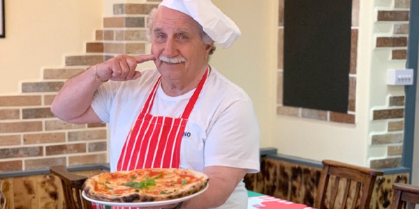 traditional italian chef with a pizza in his hands