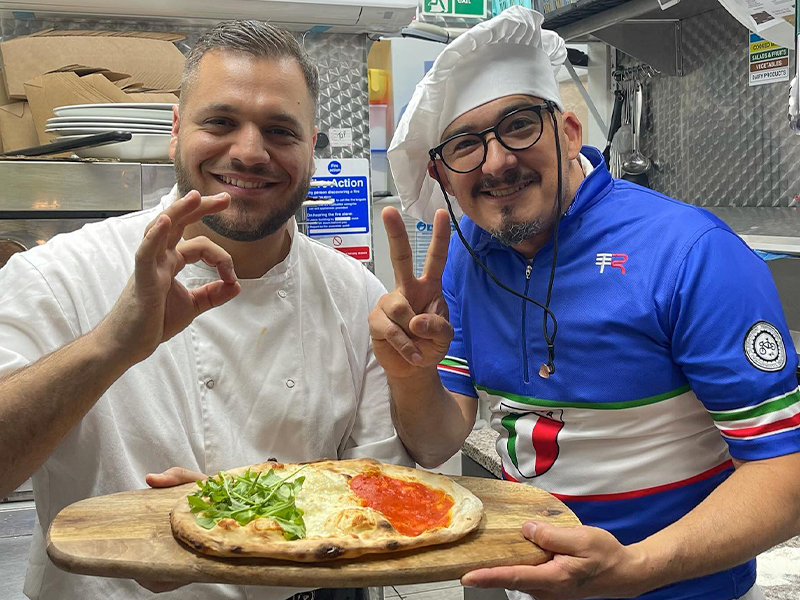 happy italian chefs holding a pizza
